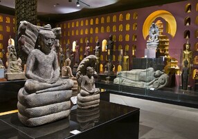 Interior de museo con esculturas de piedra y estatuas doradas en exhibición.