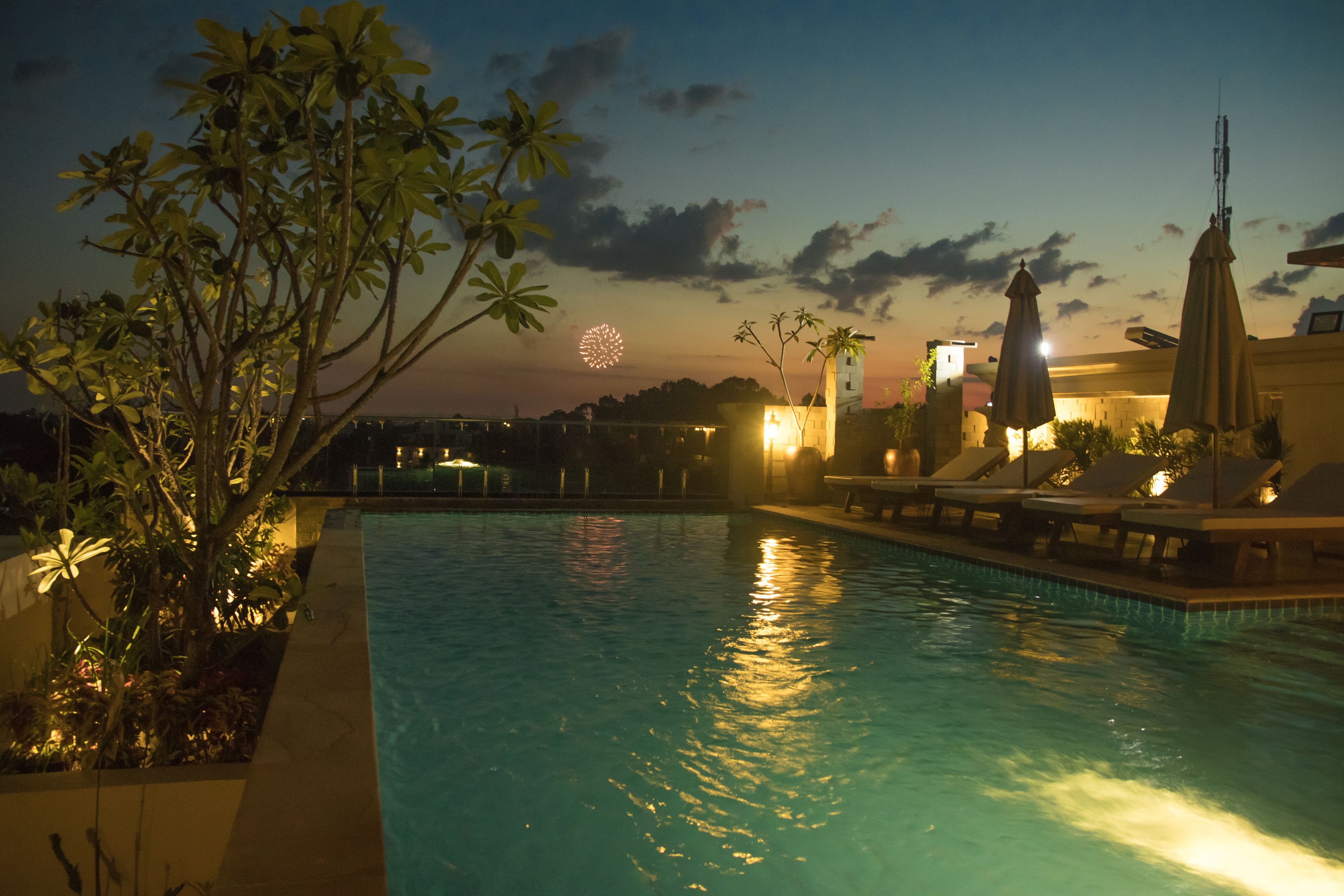 A swimming pool with lounge chairs and umbrellas, surrounded by tropical plants.