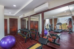 Une salle de sport équipée de matériel d’exercice, dotée d’un grand miroir et offrant une vue sur l’extérieur.