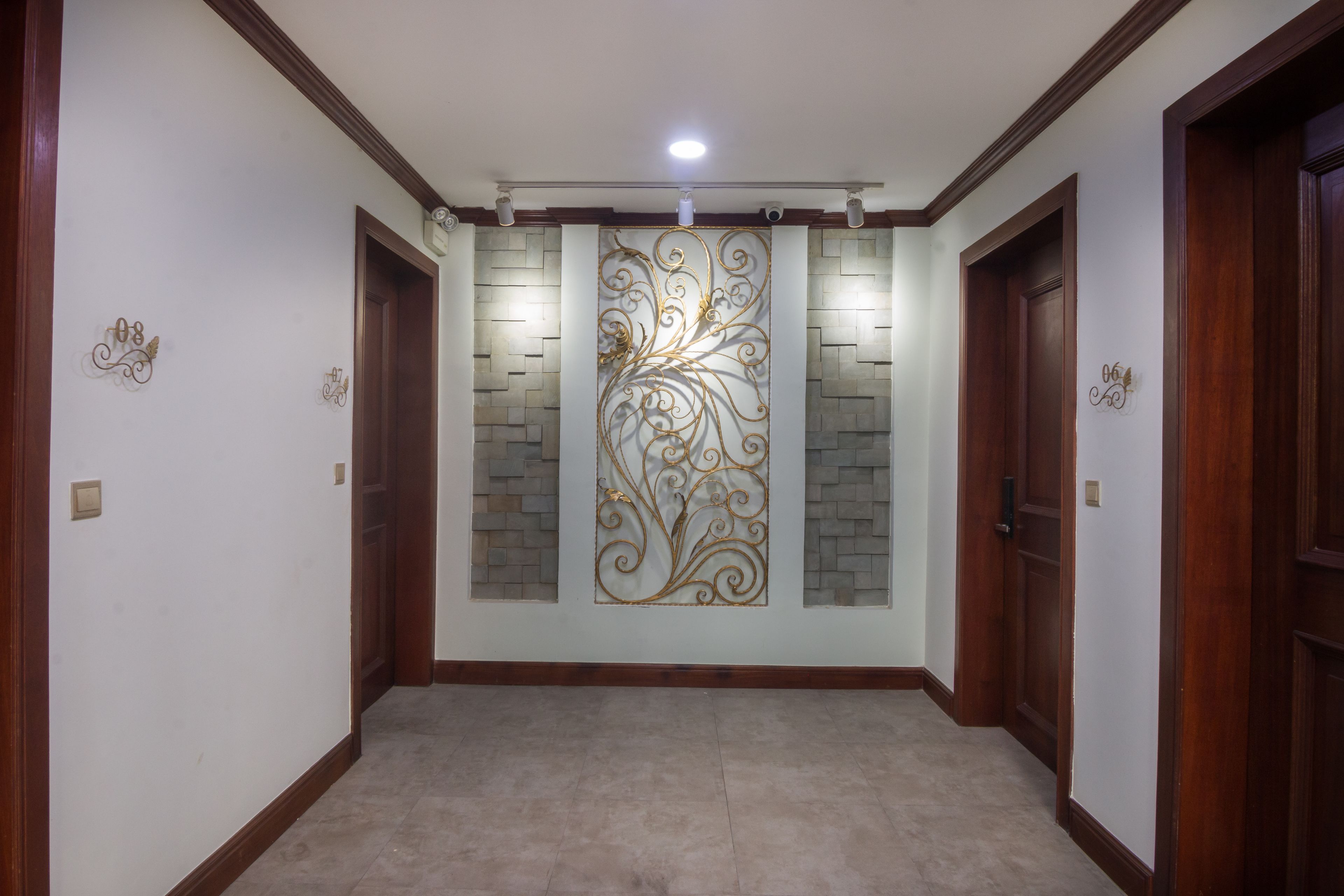 Un pasillo con un panel decorativo en la pared, puertas de madera y una lámpara.