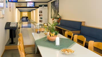 Eine Kegelbahn mit einem grünen Tisch, Stühlen und einer Blumenkomposition.