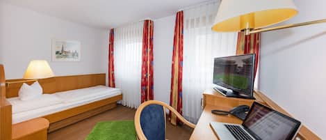A hotel room with a bed, desk, chair, and a TV.