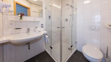 A modern bathroom with a glass-enclosed shower, a white sink, and a toilet.