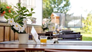 A wooden table with a potted plant, a glass of orange juice, and a menu. - Gasthof Hotel zum Ochsen (Berghülen)