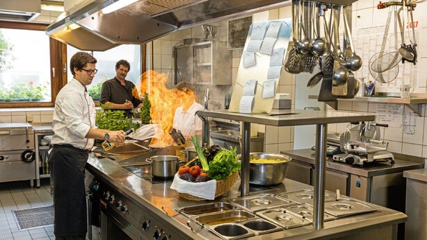 A commercial kitchen with stainless steel appliances, a buffet setup, and a fire extinguisher on the counter. - Gasthof Hotel zum Ochsen (Berghülen)