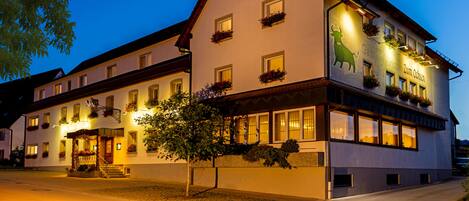 Un hotel tradicional europeo con un techo a dos aguas pronunciado, múltiples ventanas y macetas con flores.