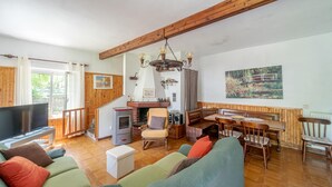 Un salon chaleureux avec une cheminée, un coin repas et une grande fenêtre.