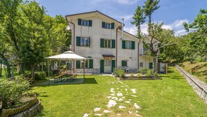 Une maison à deux étages avec un patio couvert, un chemin de pierre et un jardin.