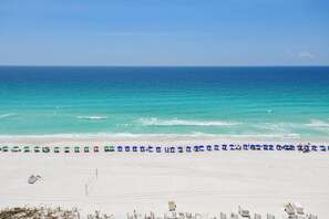 A beach with white sand and a row of umbrellas.