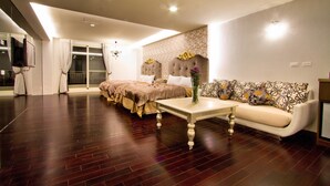 A modern bedroom with a large bed, a sofa, and a small table. - Formosa Vacation Village Homestay (Ren'ai)