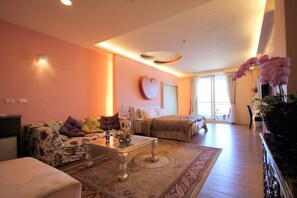 A spacious living room with a sofa, coffee table, and a heart-shaped wall decoration.