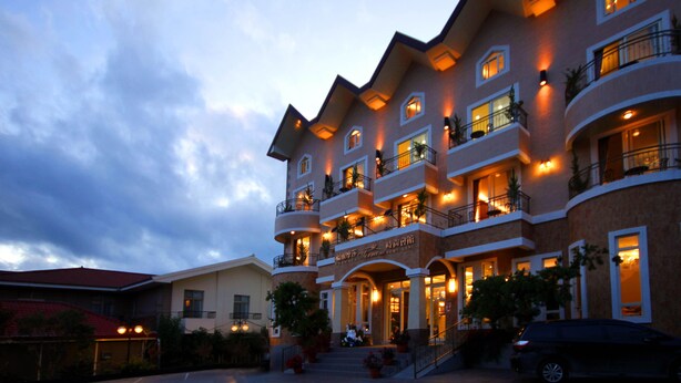 A multi-story hotel with balconies, a central entrance, and outdoor seating areas. - Formosa Vacation Village Homestay (Ren'ai)