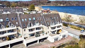 A residential building with multiple balconies, a parking area, and a view of a lake. - Smile vacation apartment right on the beach in Wassersleben (Harrislee)