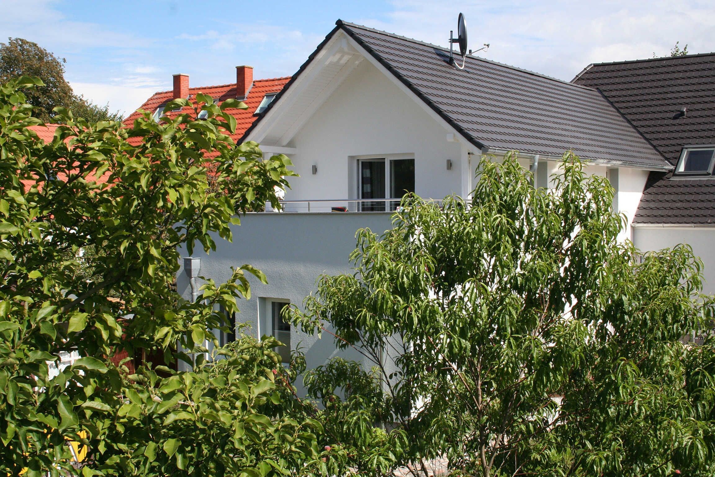 Ein modernes, zweistöckiges Haus mit rotem Dach, weißen Außenwänden und einer Satellitenschüssel.