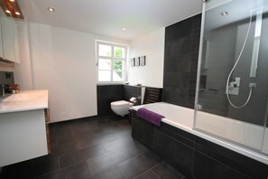 A modern bathroom with a bathtub, toilet, and shower area. - Vacation apartment Christl - Holiday apartment Christ`l (Wustrow)