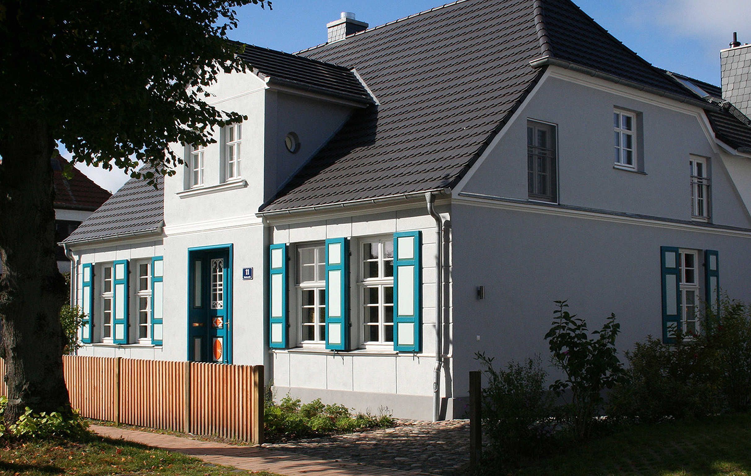 A two-story house with a sloped roof, white exterior, and blue shutters.