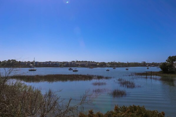 Un lac paisible où flottent plusieurs bateaux, entouré d’immeubles et d’arbres.