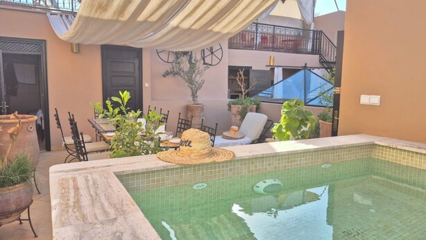 A pool area with a tiled edge, outdoor furniture, and potted plants. - RIAD L'EMPIRE in the heart of the MEDINA (Marrakech)