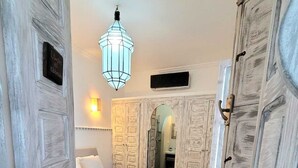 A bedroom with a bed, a nightstand, a mirror, and a hanging light fixture. - RIAD L'EMPIRE in the heart of the MEDINA (Marrakech)