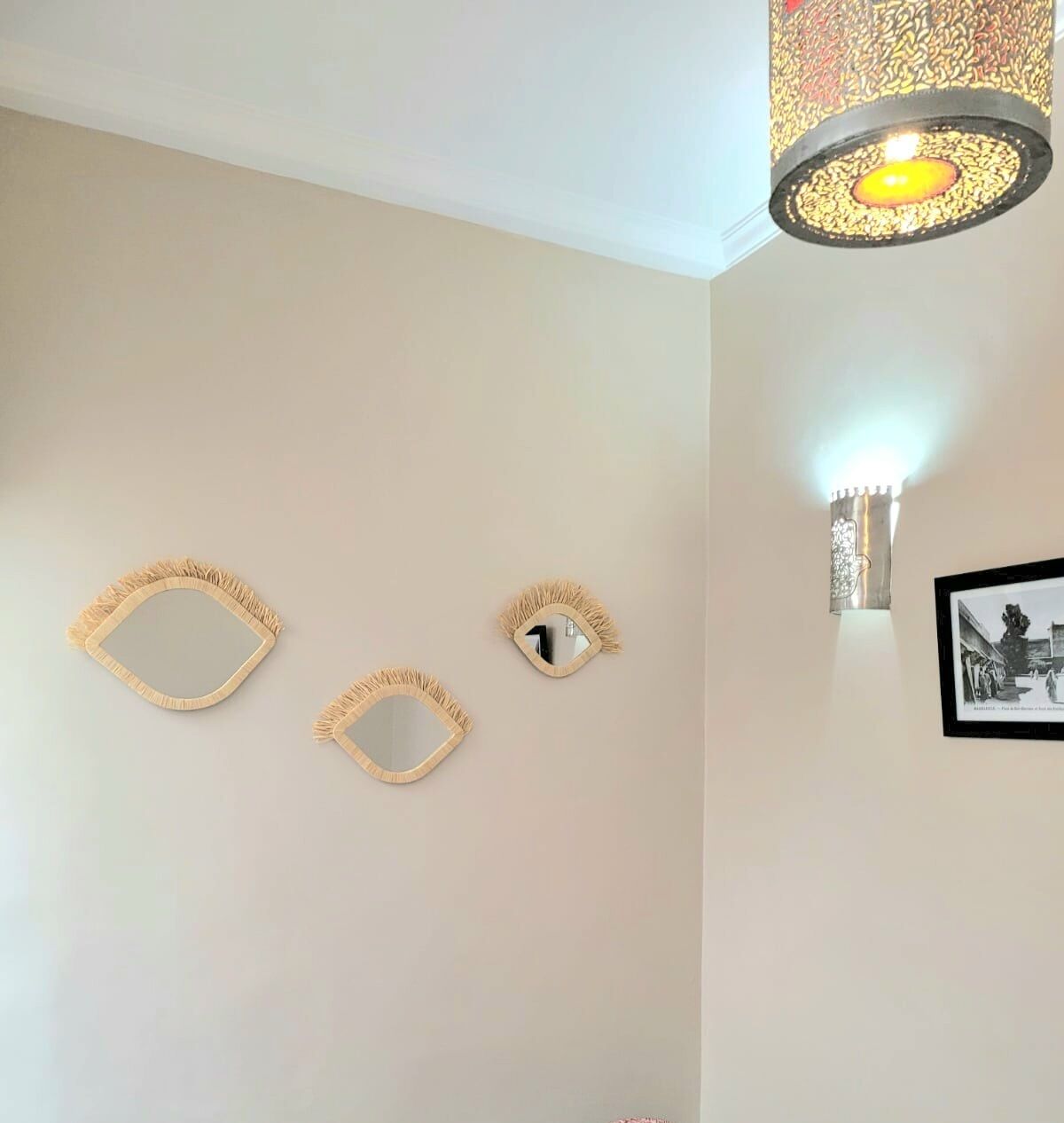 A room with two wall-mounted mirrors and a decorative light fixture.