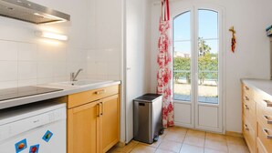 Una cocina moderna con baldosas blancas, armarios de madera, lavavajillas de acero inoxidable y un cubo de basura.