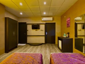 A hotel room with two beds, a television, a minibar, and an air conditioning unit. - Ace Prime Hotel (Greater Noida)
