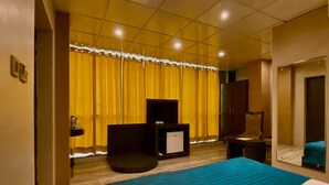 A hotel room with a bed, a TV, a desk, and a wardrobe. - Ace Prime Hotel (Greater Noida)