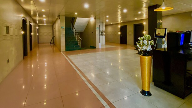 A spacious lobby with a reception desk, a staircase, and a large vase of flowers. - Ace Prime Hotel (Greater Noida)