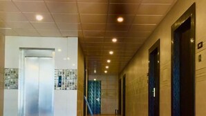 A clean, modern hallway with a shiny floor, a reception area, and elevators. - Ace Prime Hotel (Greater Noida)
