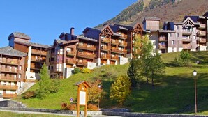 A hotel with multiple wooden balconies, a signboard, and a mountainous backdrop. - Comfortable 1-Bedroom Apt with Balcony, Pets Allowed in Valmorel (Valmorel)