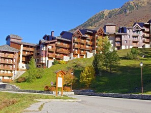 A hotel with multiple wooden balconies, a signboard, and a mountainous backdrop. - Comfortable 1-Bedroom Apt with Balcony, Pets Allowed in Valmorel (Valmorel)