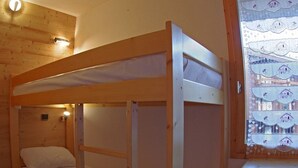 A bunk bed room with a wooden ceiling and a window with a lace curtain. - Comfortable 1-Bedroom Apt with Balcony, Pets Allowed in Valmorel (Valmorel)