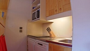 A compact kitchen with a microwave, sink, and wooden cabinets. - Comfortable 1-Bedroom Apt with Balcony, Pets Allowed in Valmorel (Valmorel)