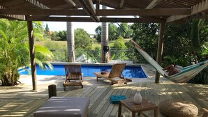 Eine Holzterrasse mit Liegestühlen, einem kleinen Tisch und einer Hängematte.