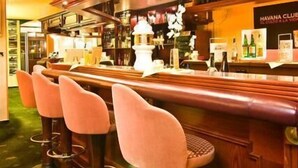 Un espace bar avec des lambris en bois, un comptoir et des tabourets de bar.