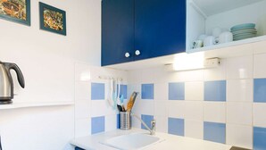 Een keuken met blauwe kastjes, een wit aanrecht en een ingebouwde kookplaat.