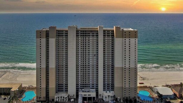 A high-rise hotel with a pool area and a view of the ocean at sunset. - BOOK SUMMER NOW. GREAT RATES! Gulf-Front Master w/Balcony + PRIVATE Bunkroom (Panama City Beach)