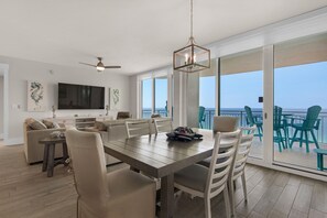 Un vaste espace de vie comprenant une grande table à manger, des sièges confortables, un ventilateur de plafond et un téléviseur.