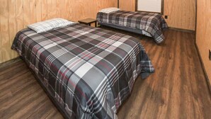 A room with two beds, each with a plaid bedspread, wooden flooring, and a window with blinds. - Mid- Lake home, perfect for a group w/ lots of boat and truck parking (Scottsboro)