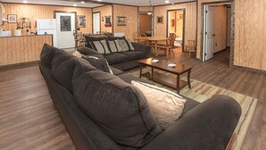A cozy living room with a dark brown sofa, a wooden coffee table, and a dining area with wooden chairs and a table. - Mid- Lake home, perfect for a group w/ lots of boat and truck parking (Scottsboro)