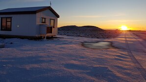 A small, single-story cabin with a sloped roof, a visible antenna, and a door with a window above it.