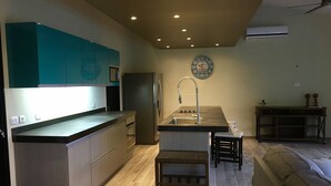 Una cocina moderna con una isla central, electrodomésticos integrados y una zona de comedor con banco.