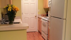Une cuisine avec des meubles de rangement en bois, un réfrigérateur blanc, une cuisinière et un évier.
