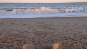 Une plage de sable avec un château de sable au premier plan et des vagues qui se rapprochent du rivage.
