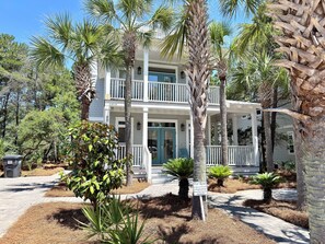 A two-story house with a balcony, surrounded by palm trees and a landscaped garden. - Stunning 30a renovation! 4BR Seacrest Beach near Rosemary, Walk to Pool-Beach (Rosemary Beach)