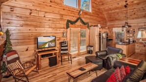 A cozy cabin interior with wooden walls, a television, a fireplace, a dining area, and a kitchen. - Highland Dream, Hot Tub, FREE tickets each paid day, Near Dollywood, WIFI!!! (Sevierville)