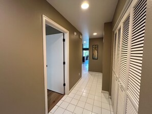 A hallway with a white door, beige walls, and a tiled floor.
