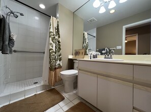 A modern bathroom with a shower, toilet, and vanity.