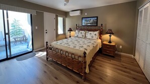 A bedroom with a large bed, a ceiling fan, a nightstand with a lamp, and a sliding glass door leading to a patio. - Maui Kamaole #L-105 Beautiful Ocean View, Great Location, Great Rates, A/C (Kihei)