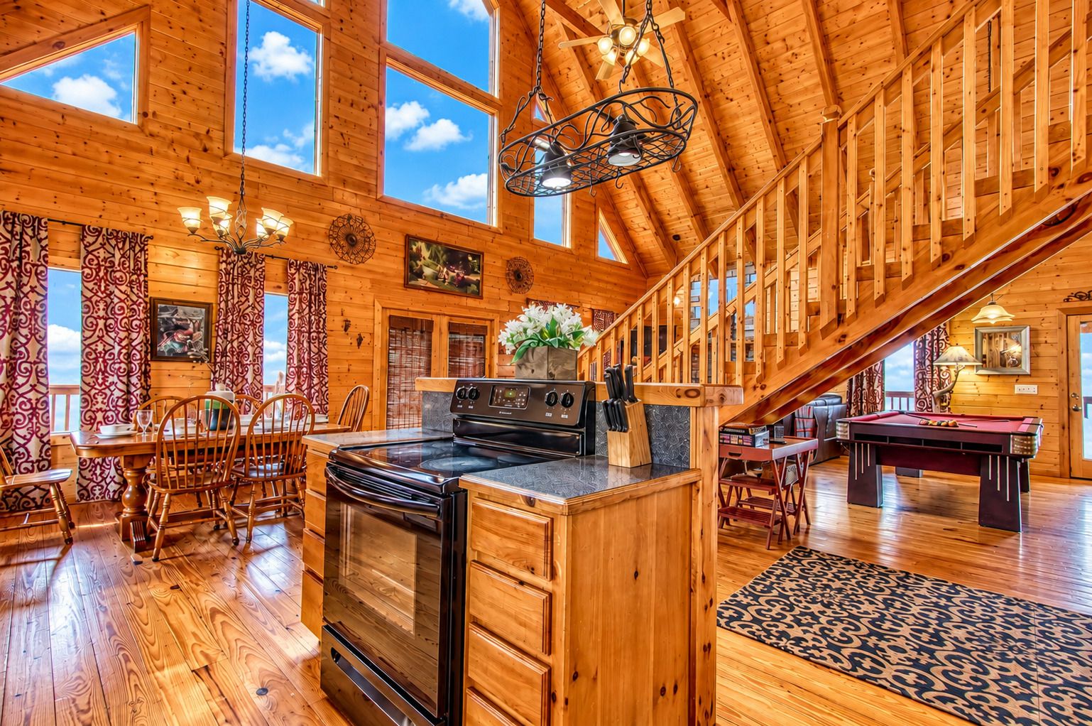 A spacious wooden cabin with a dining area, kitchen, and pool table.